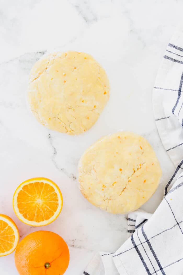 These cute blueberry hand pies combine a flaky pastry crust with sweet blueberry pie filling. It's so much easier than baking a whole pie! Overhead view of two flattened discs of pastry dough.