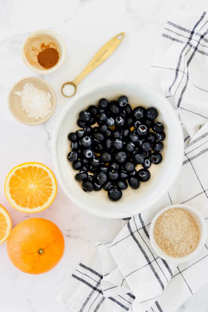 These cute blueberry hand pies combine a flaky pastry crust with sweet blueberry pie filling. It's so much easier than baking a whole pie! Overhead view of blueberries combined with orange juice in a bowl.