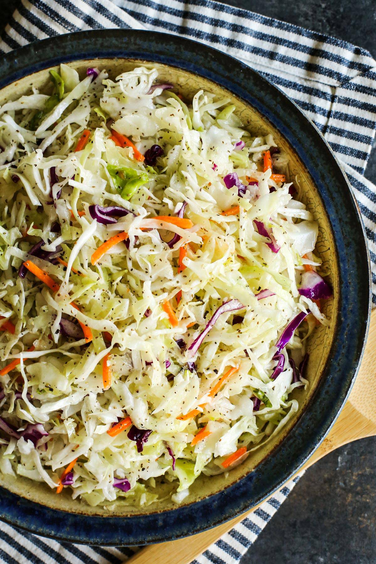 This Sweet Onion Vinegar Coleslaw recipe is fresh, bright & tangy. No mayo here! It has a coleslaw dressing that's seriously good! coleslaw dressing on shredded cabbage in a pottery bowl