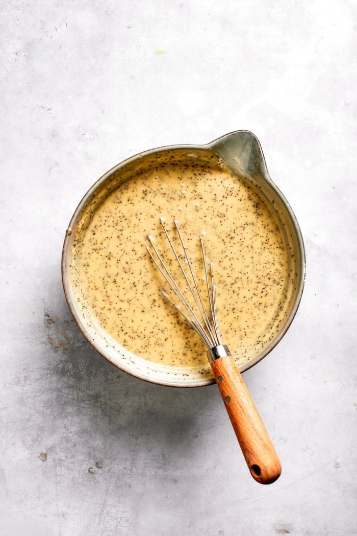 This Almond Lemon Poppy Seed Bread is soft, moist and citrusy. Topped with a zesty glaze, it’s breakfast bread worth getting out of bed for! Bowl of batter for almond lemon poppy seed bread with whisk.