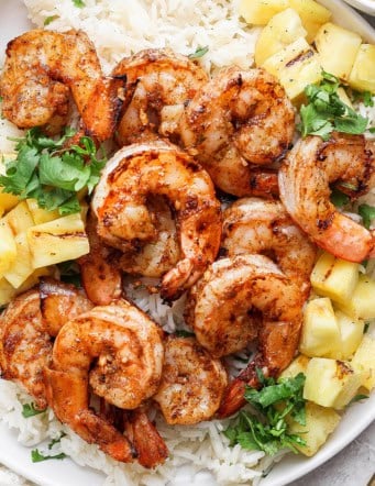 Overhead view of grilled jerk shrimp on plate with cilantro lime rice and pineapple