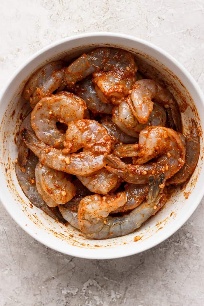 Enjoy this grilled jerk shrimp recipe as a tantalizing appetizer, gorgeous salad topper, or main entrée. It's quick, easy, and so flavorful! Bowl of shrimp in jerk marinade