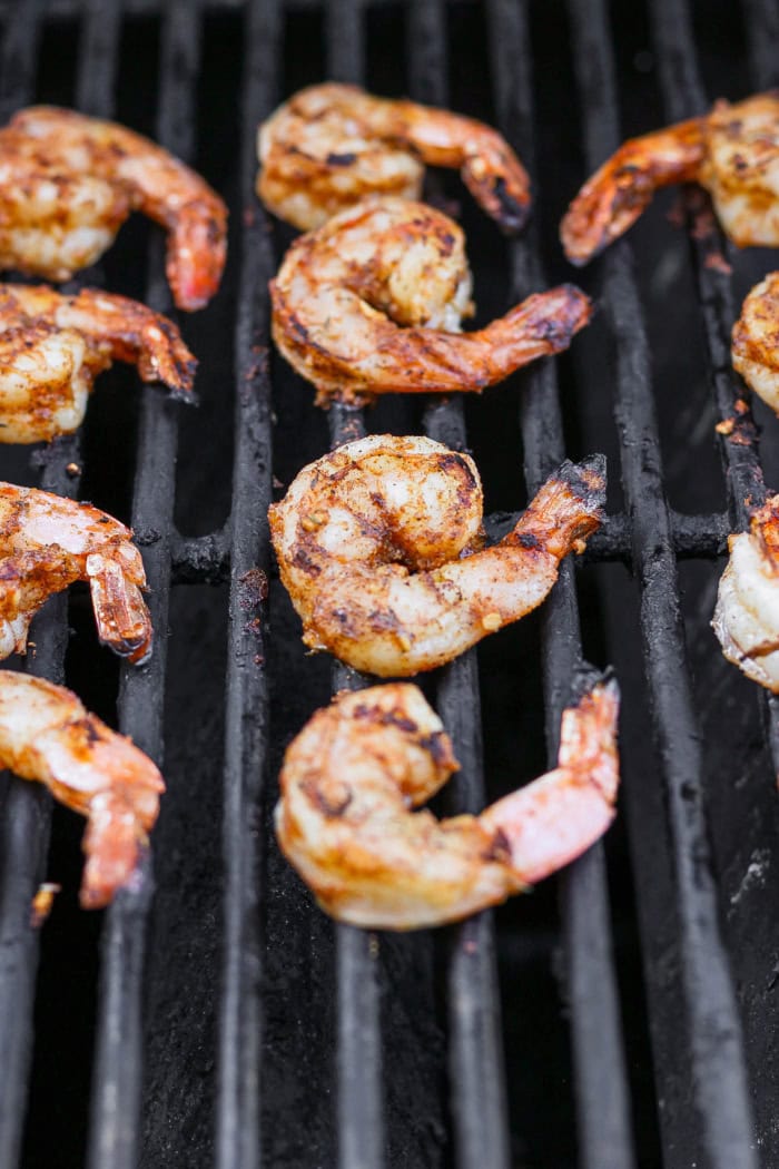Enjoy this grilled jerk shrimp recipe as a tantalizing appetizer, gorgeous salad topper, or main entrée. It's quick, easy, and so flavorful! Jerk shrimp cooking on grill