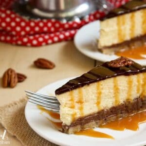 two slices of Turtle Pecan Cluster Cheesecake drizzled with caramel
