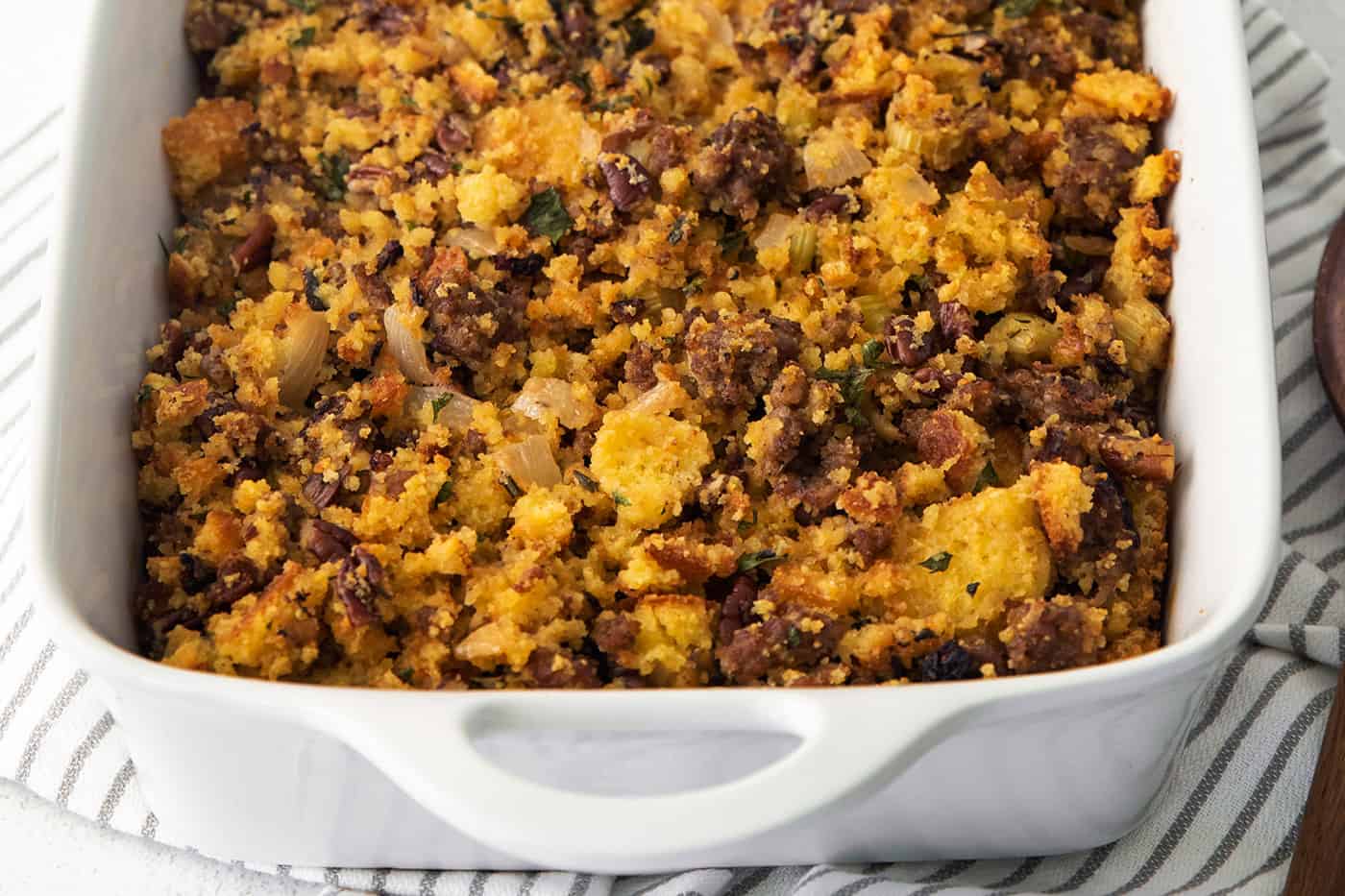 Cornbread sausage dressing in a white casserole dish.