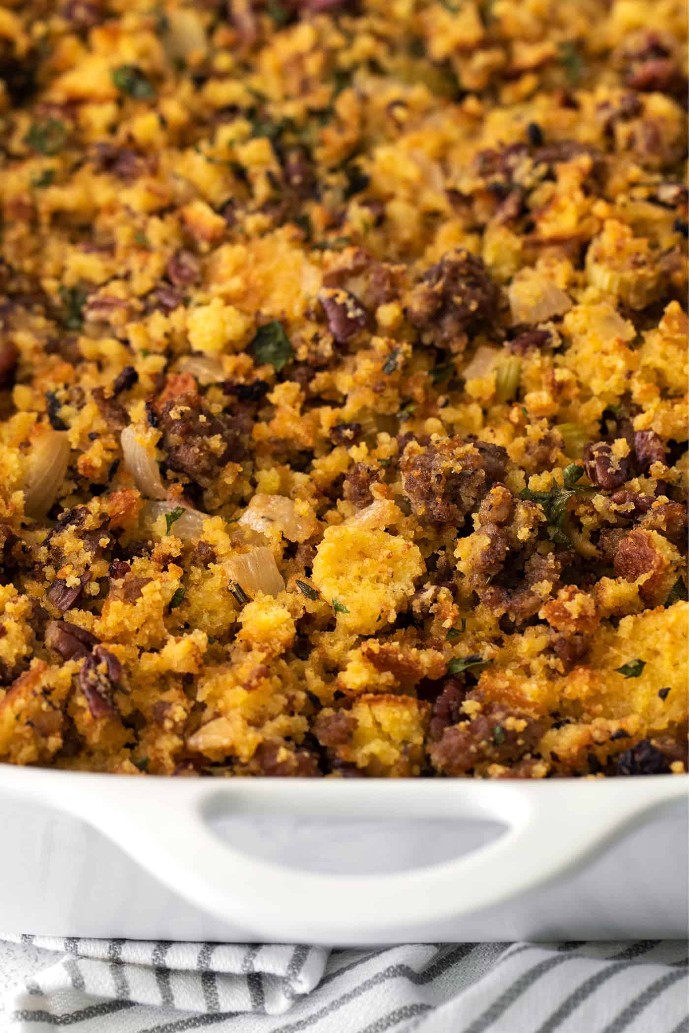Close-up of cornbread dressing with sausage in a casserole dish.