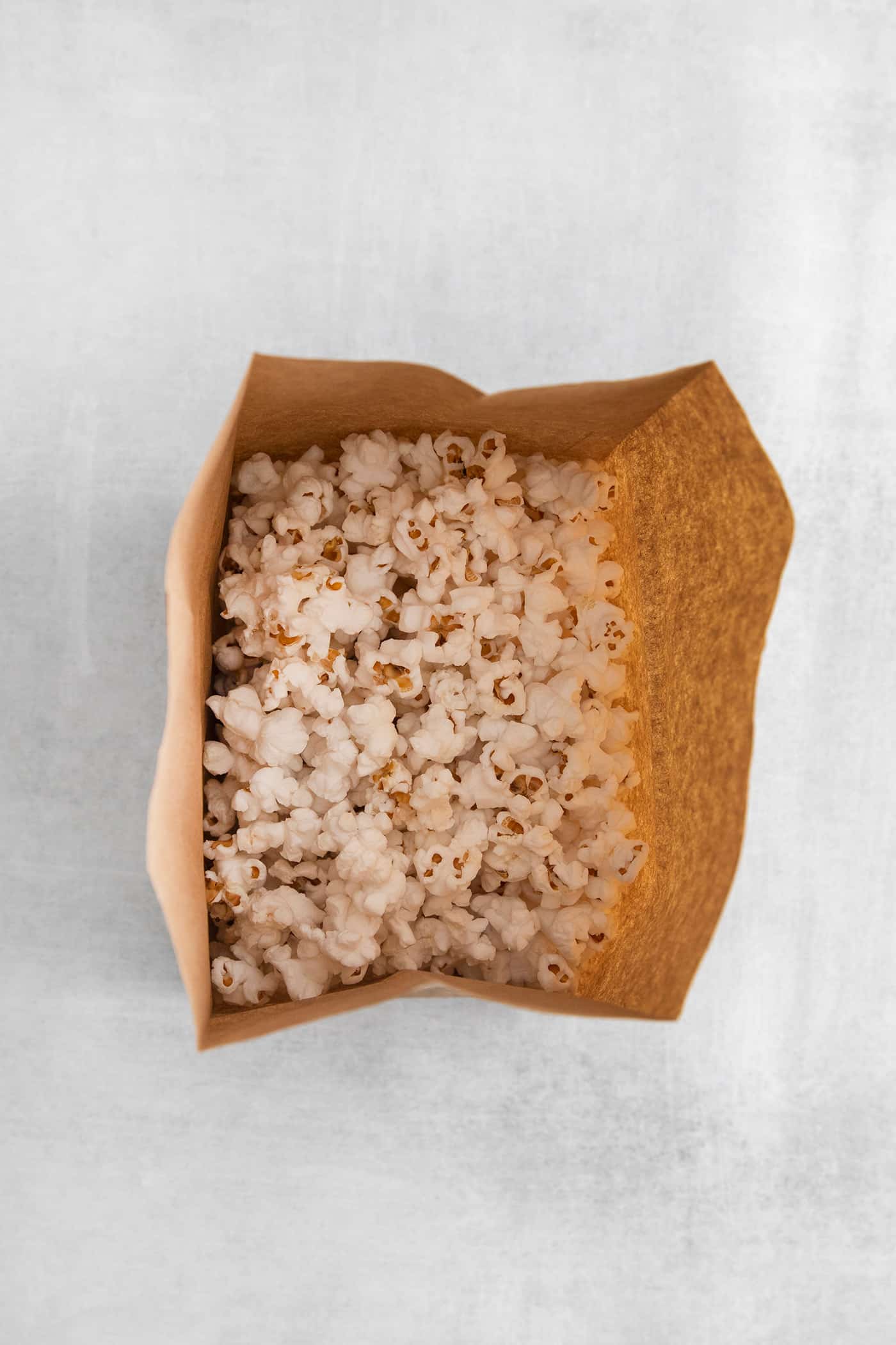 Microwave Caramel Popcorn is ready in just 15 minutes, with a handful of ingredients, a microwave, and a brown paper bag. Popped popcorn in a brown paper bag
