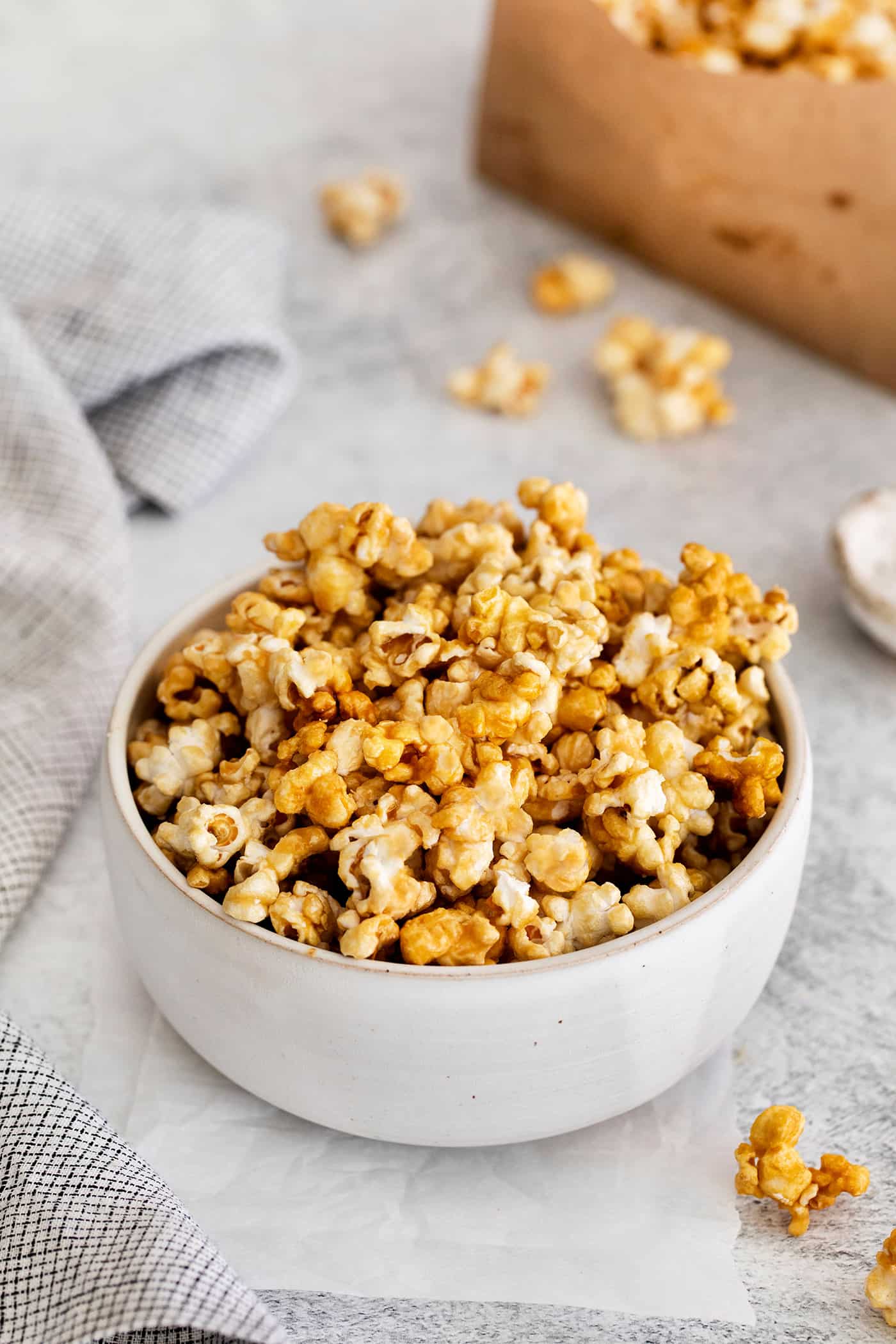 Microwave Caramel Popcorn is ready in just 15 minutes, with a handful of ingredients, a microwave, and a brown paper bag. Angled view of a bowl of caramel popcorn