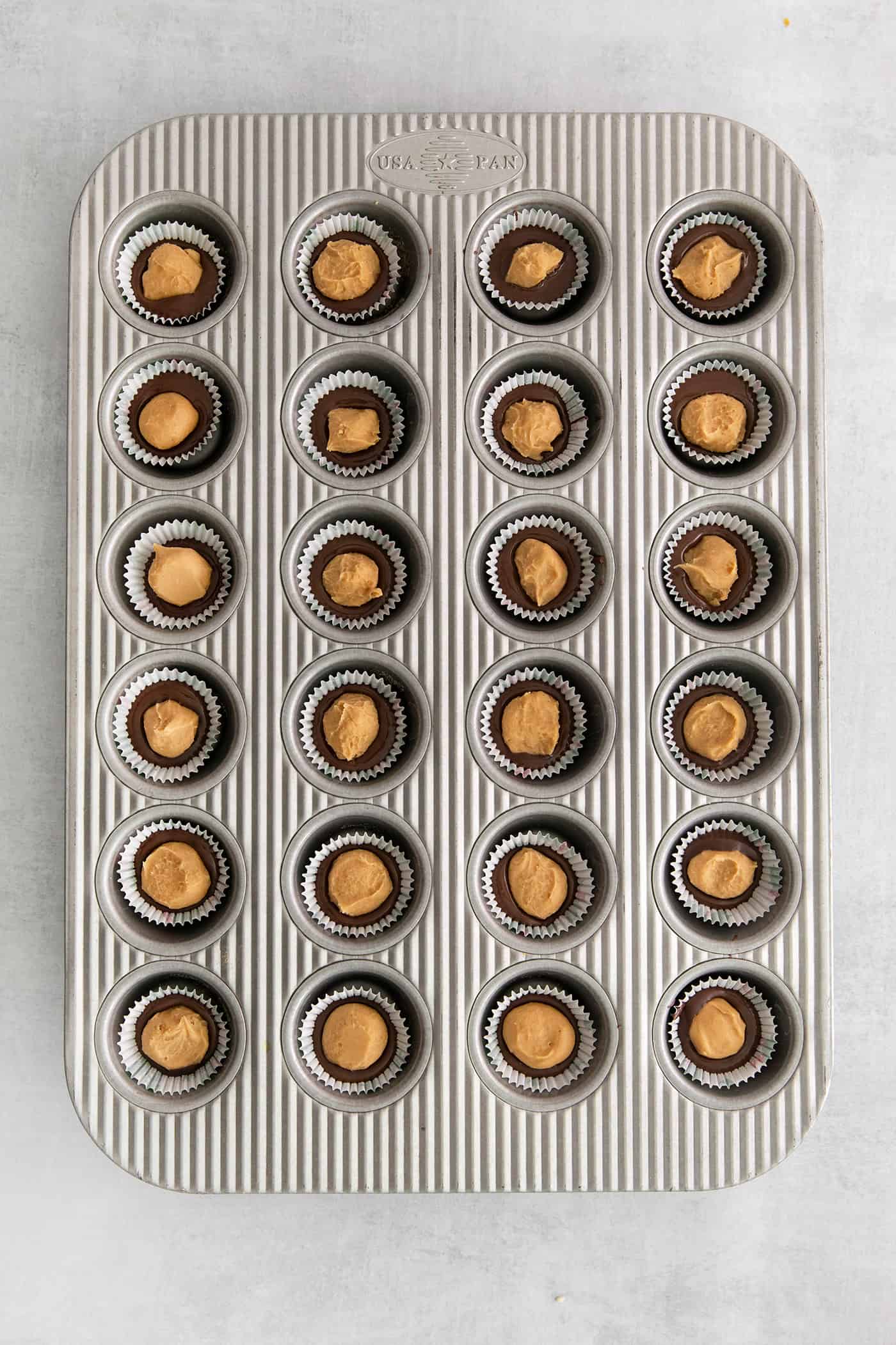 Made with just 5 ingredients, these Homemade Peanut Butter Cups are a million times better than anything you can buy at the store. Overhead view of peanut butter balls in mini muffin tins