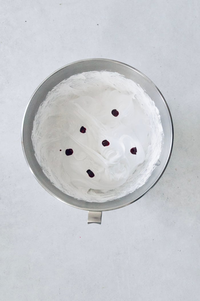 Homemade peppermint marshmallows are fluffy, festive, and so delicious! They're perfect for gifting, hot cocoa, and holiday treats. Food coloring added to marshmallow mixture in mixing bowl.