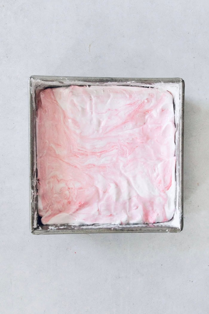 Homemade peppermint marshmallows are fluffy, festive, and so delicious! They're perfect for gifting, hot cocoa, and holiday treats. Peppermint marshmallows in pan before slicing.