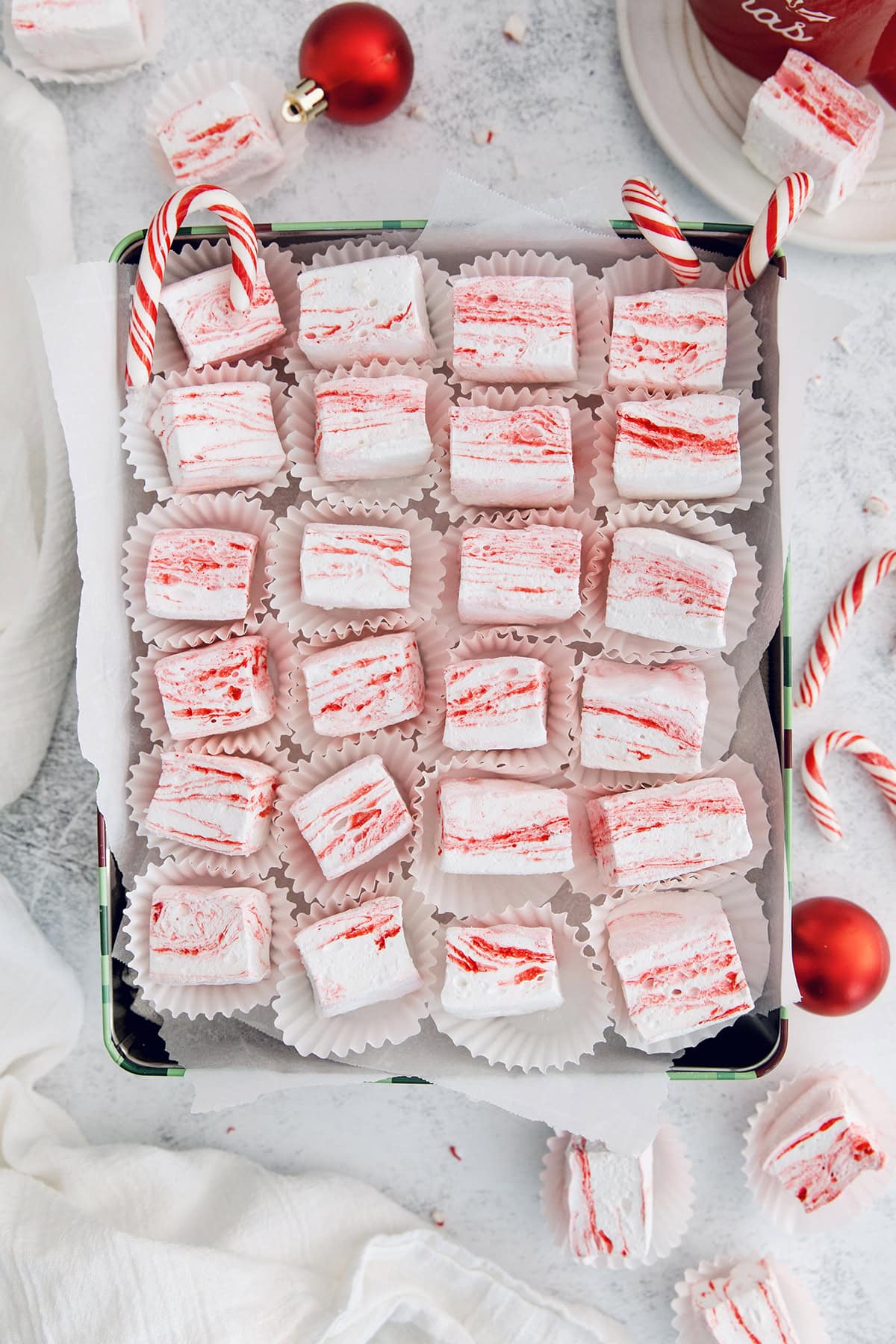 Homemade peppermint marshmallows are fluffy, festive, and so delicious! They're perfect for gifting, hot cocoa, and holiday treats. Box of homemade peppermint marshmallows in cupcake wrappers.