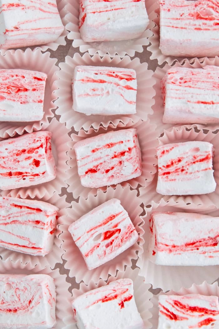 Homemade peppermint marshmallows are fluffy, festive, and so delicious! They're perfect for gifting, hot cocoa, and holiday treats. Peppermint marshmallows in cupcake wrappers.