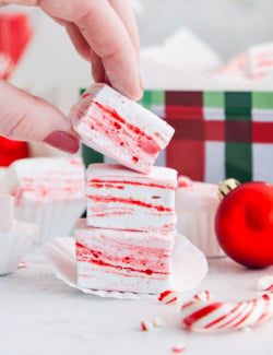 Hand lifting peppermint marshmallow from stack.