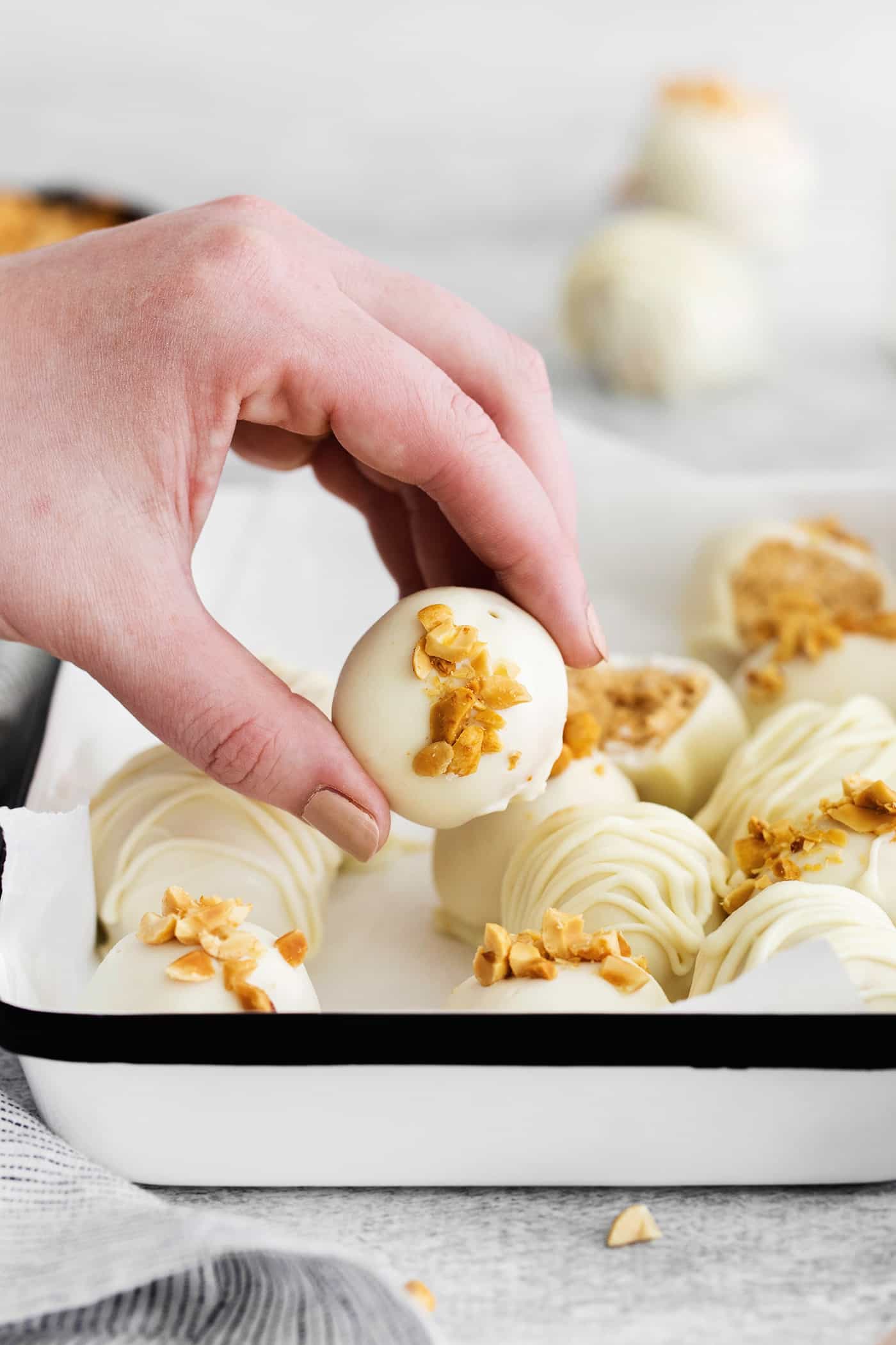 Made with just 5 ingredients, these Peanut Butter Truffles with Rice Krispies and Marshmallows are the perfect bite-sized treat. A hand grabbing a peanut butter truffle with rice krispies