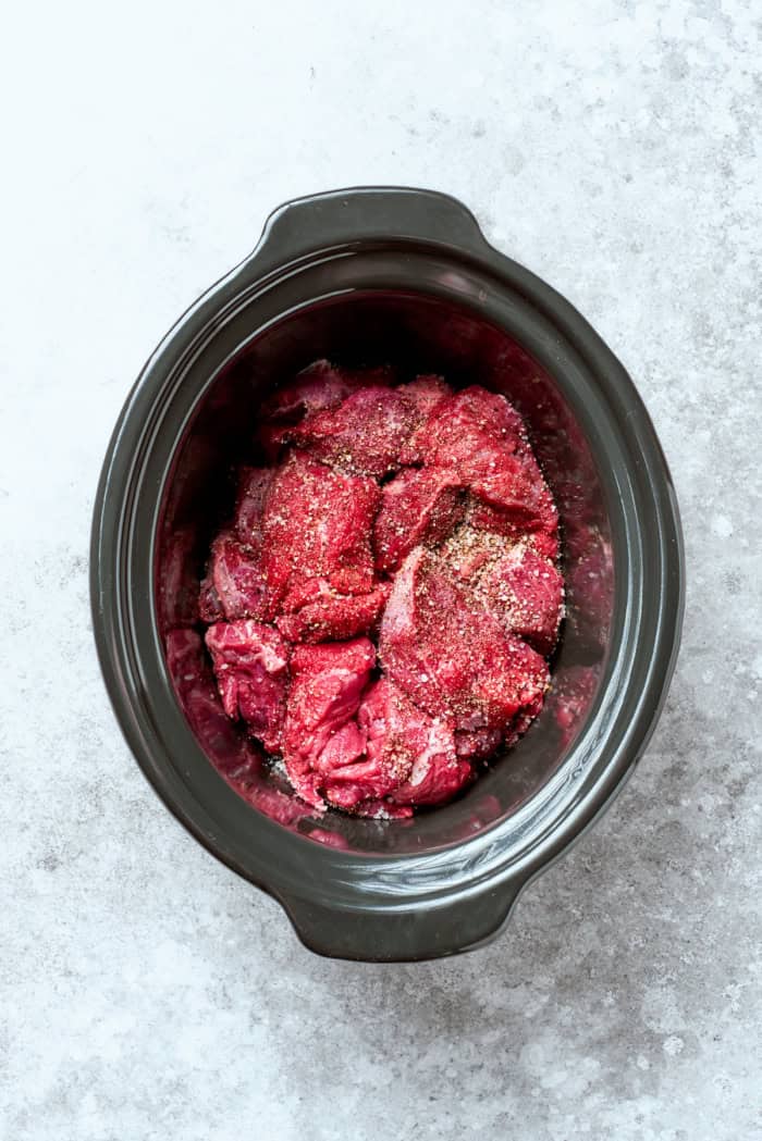 With fall-apart tender beef, fragrant spices, and a creamy coconut broth, this easy Slow Cooker Beef Curry is even better than takeout! Overhead view of seasoned beef in crockpot