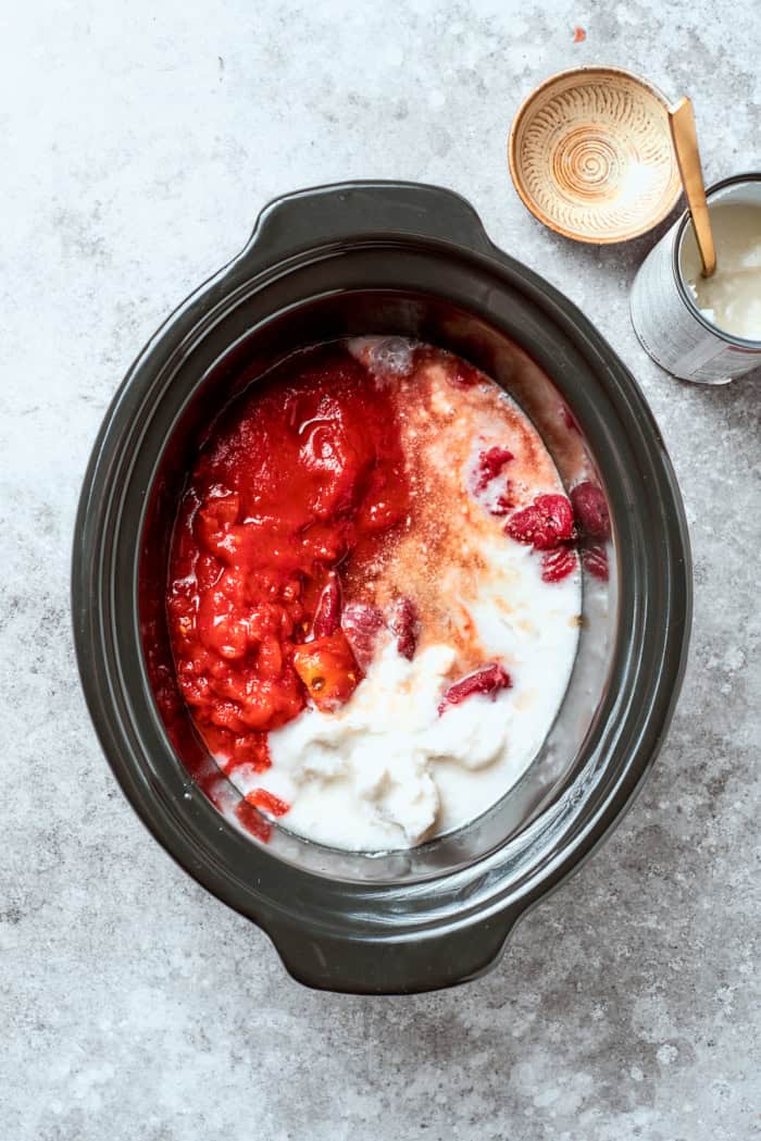 With fall-apart tender beef, fragrant spices, and a creamy coconut broth, this easy Slow Cooker Beef Curry is even better than takeout! Overhead view of coconut milk, tomato paste, and crushed tomatoes added to crockpot