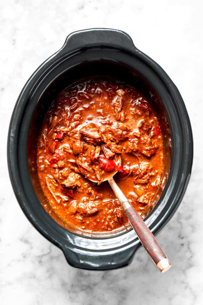 With fall-apart tender beef, fragrant spices, and a creamy coconut broth, this easy Slow Cooker Beef Curry is even better than takeout! Overhead view of slow cooker beef curry in crockpot with spoon