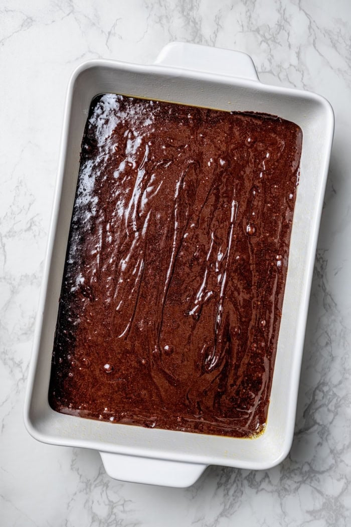 These fudgy cherry brownies are layered with fluffy cherry buttercream and smooth chocolate glaze for an indulgent bakery-style dessert! Brownie batter in pan.
