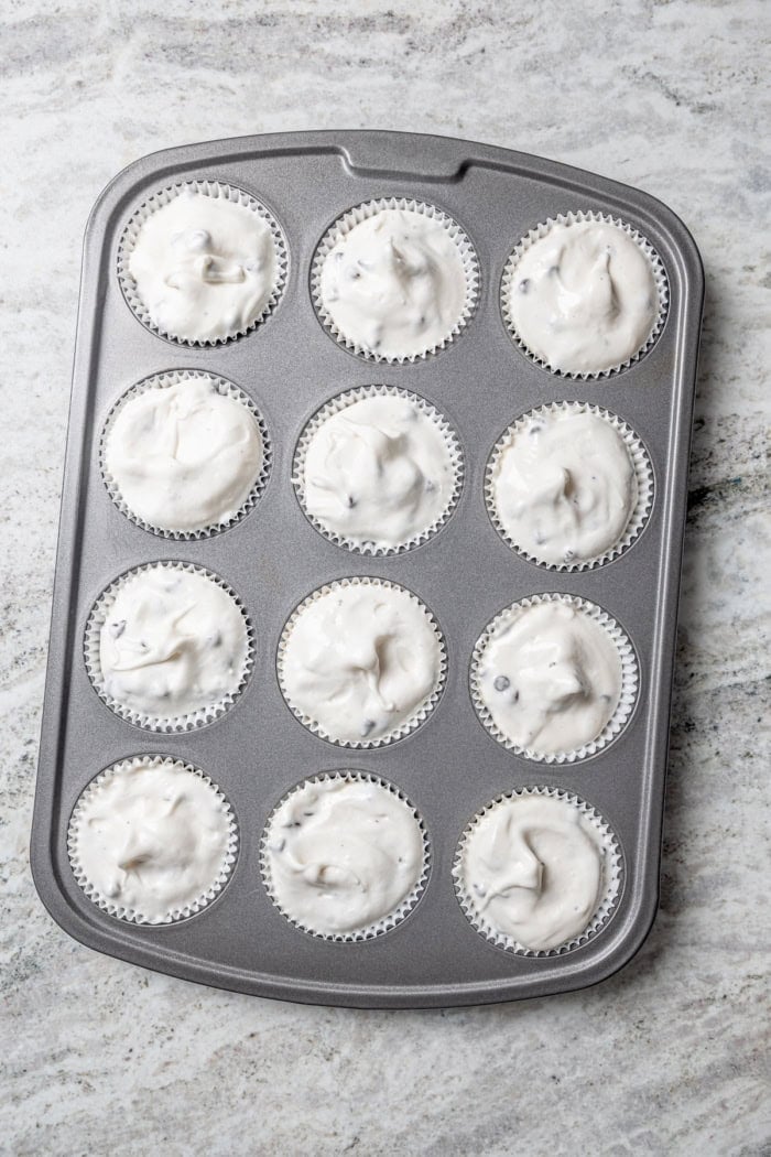 These Angel Food Cupcakes are dotted with mini chocolate chips and topped with vanilla cream and fresh berries. A light, summery treat! Overhead view of unbaked angel food cupcakes in pan