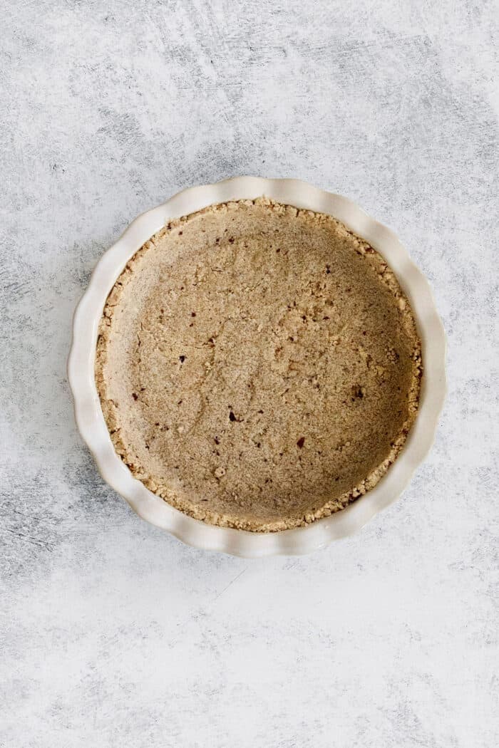 This lighter-than-air French silk pie recipe with 2 types of chocolate, espresso, and a salted pecan crust is a decadent holiday treat. Baked crust in the pie dish.