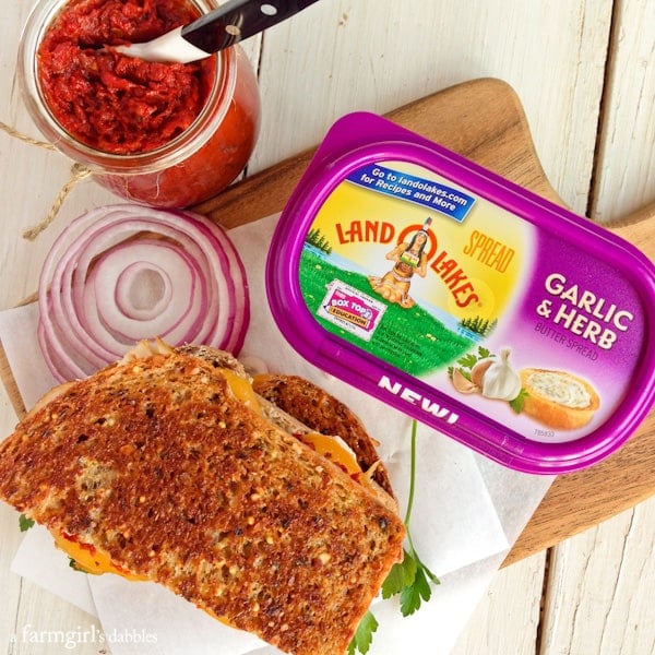 a tub of land o lakes garlic and herb butter with half of a grilled Cheese Sandwich