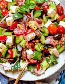 Overhead view of chopped Greek salad in bowl with spoon