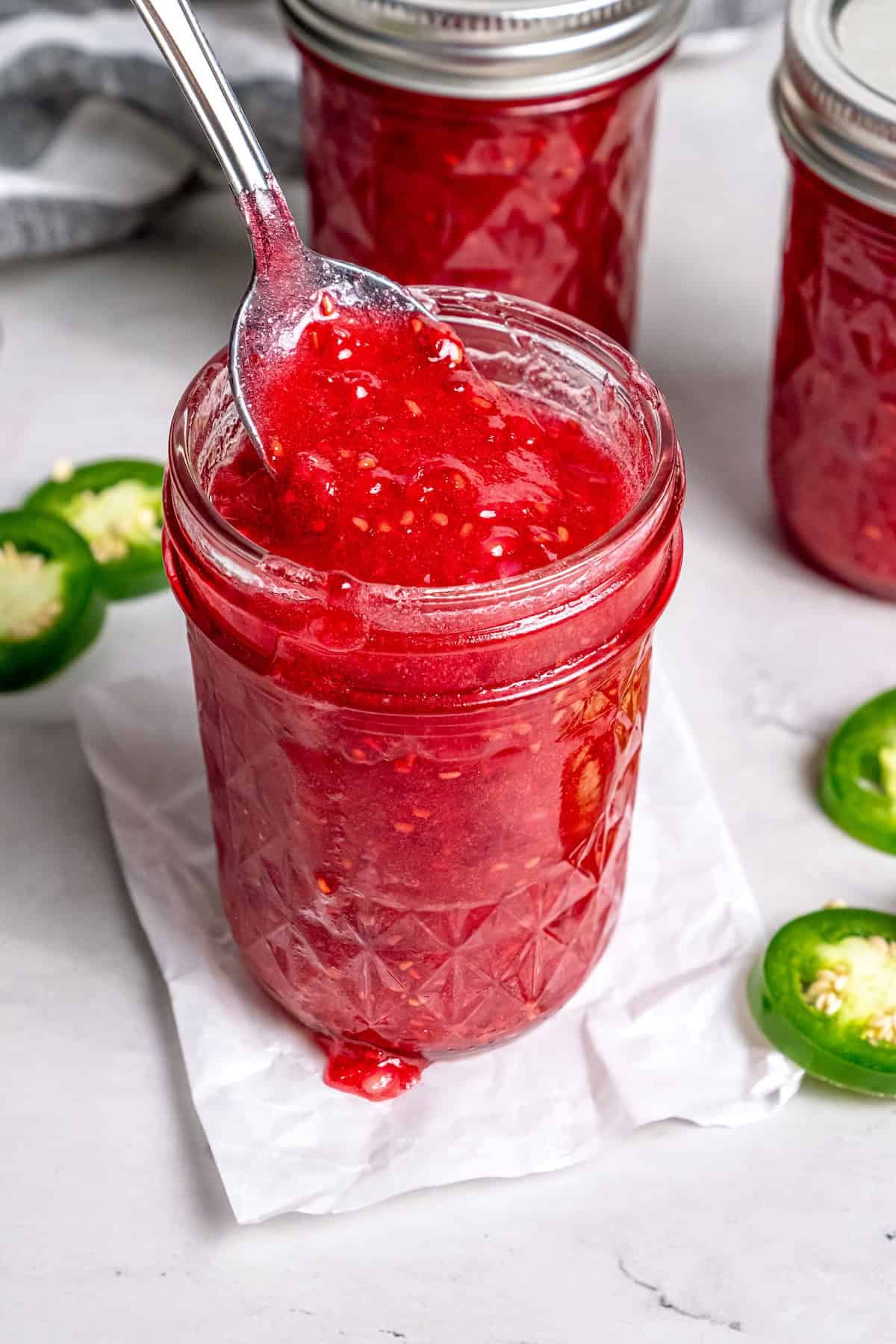 This Raspberry Freezer Jam is the easiest you'll ever make—no canning needed! It's a delicious way to extended the life of your berries. Jar of raspberry freezer jam with jalapeños