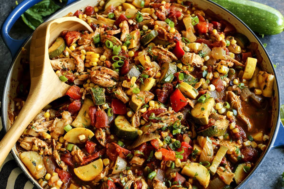 Shredded chicken and summer vegetables are the stars of this Chicken Chili recipe that's packed with zucchini, summer squash, and fresh herbs. End of Summer Chicken Chili with a wood serving spoon