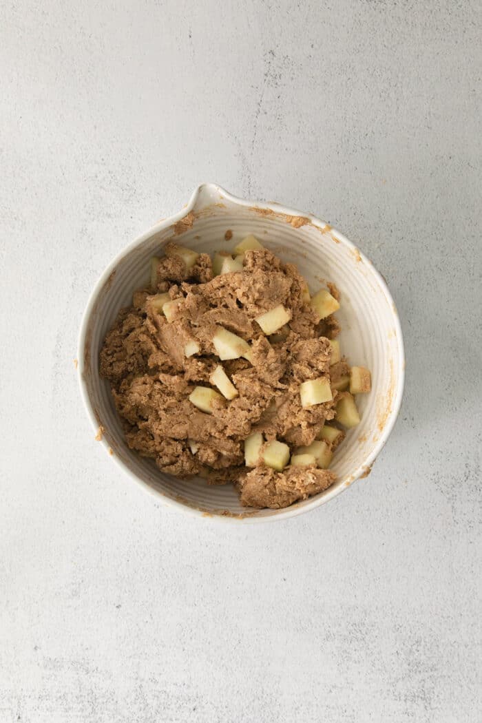 Make moist, tender apple muffins studded with juicy apple bites! Topped with cinnamon streusel, these easy muffins are great for fall baking. Apples being stirred into muffin batter