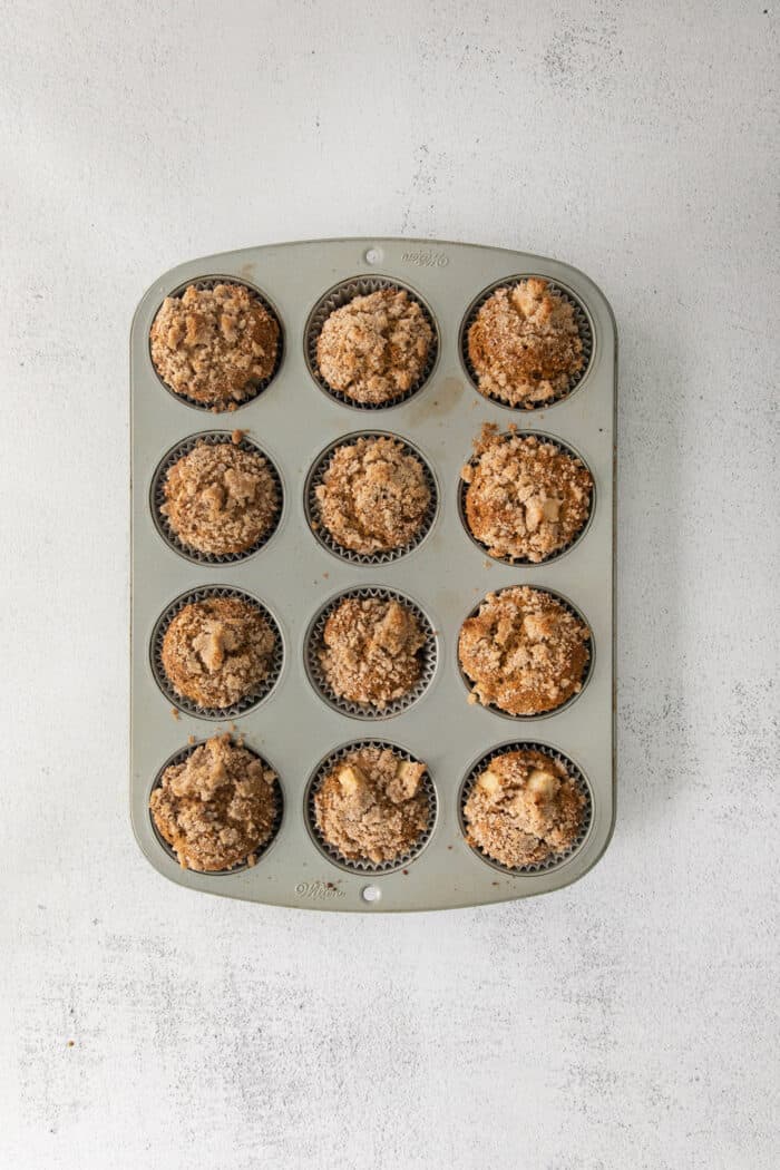 Make moist, tender apple muffins studded with juicy apple bites! Topped with cinnamon streusel, these easy muffins are great for fall baking. Apple muffins in a muffin tin