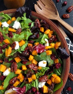 Harvest salad with butternut squash in a wooden bowl.