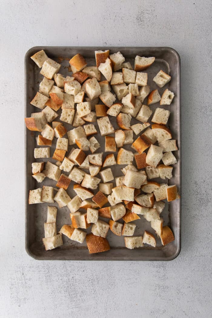 This savory dressing with mushrooms, pork sausage, crispy garlic breadcrumbs, and Parmesan is the best Thanksgiving stuffing recipe! Croutons on a baking sheet