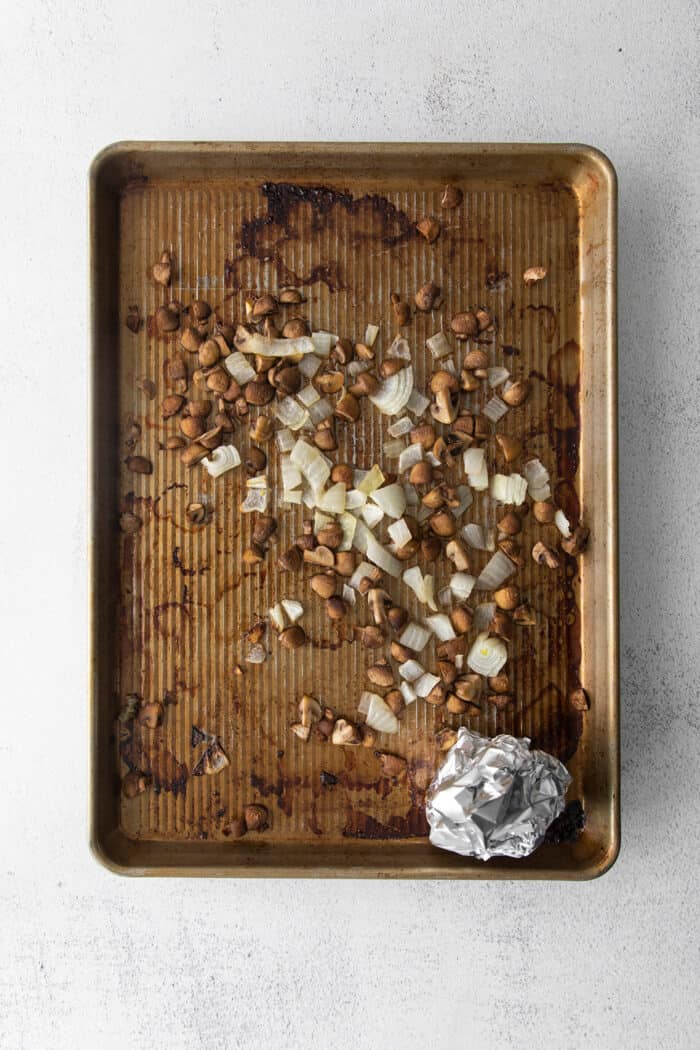 This savory dressing with mushrooms, pork sausage, crispy garlic breadcrumbs, and Parmesan is the best Thanksgiving stuffing recipe! Overhead view of a sheet pan with a roasted garlic clove