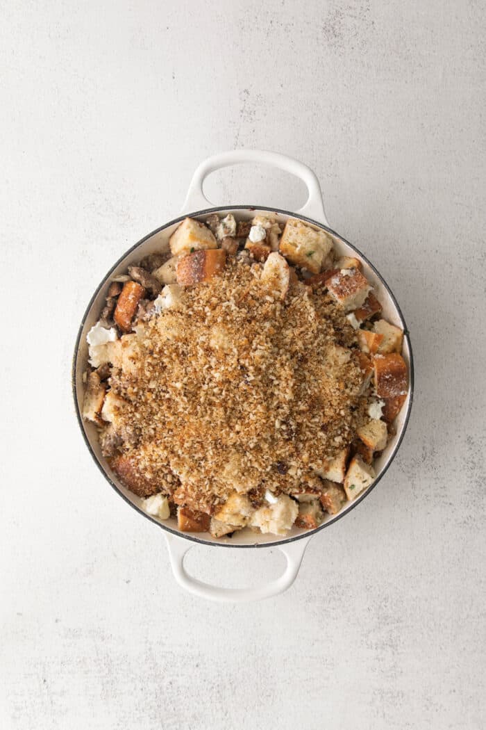 This savory dressing with mushrooms, pork sausage, crispy garlic breadcrumbs, and Parmesan is the best Thanksgiving stuffing recipe! Overhead view of mushroom stuffing topped with breadcrumbs in a casserole dish.