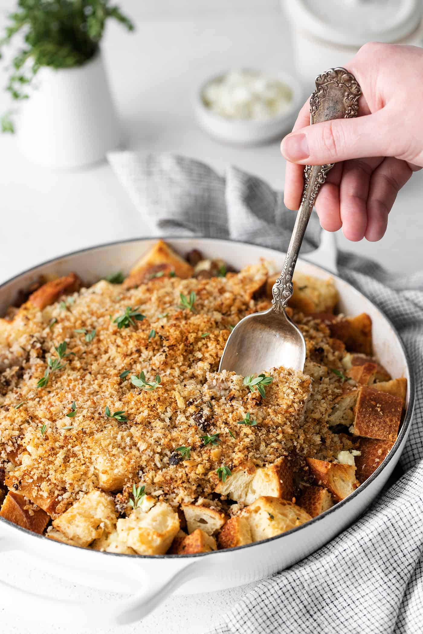 This savory dressing with mushrooms, pork sausage, crispy garlic breadcrumbs, and Parmesan is the best Thanksgiving stuffing recipe! A spoon serving dressing with mushrooms and sausage from a casserole dish.