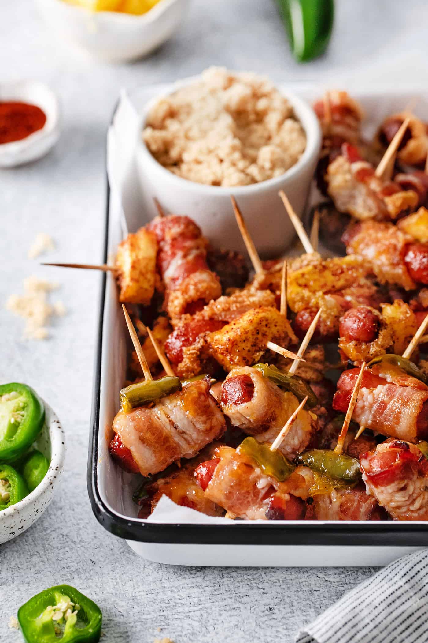 These Bacon Wrapped Smokies are the perfect game day appetizer. Switch things up by adding pineapple or jalapeno slices! Close-up of bacon wrapped smokies on a serving dish