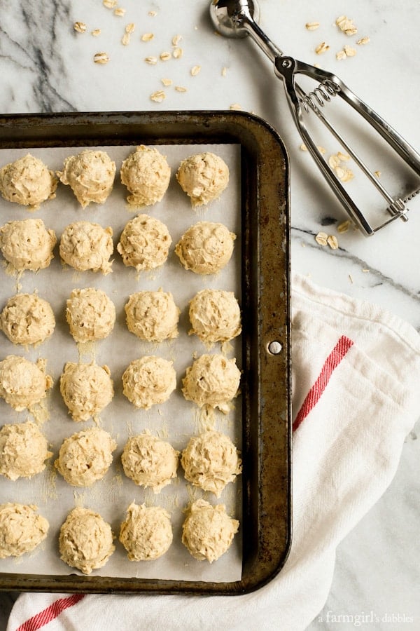 Peanut butter sandwich cookies combine soft, chewy peanut butter cookies with a rich and creamy filling, for double the flavor in every bite! Overhead view of scoops of peanut butter cookie dough in rows on a parchment lined baking sheet.