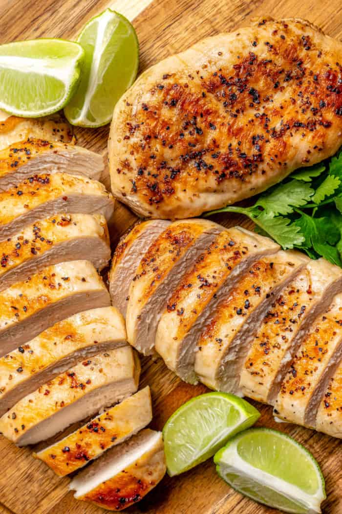 This Grilled Chicken Salad combines fresh corn, creamy avocado and juicy tomatoes with a zippy cilantro-lime vinaigrette for one tasty salad! Overhead view of sliced grilled chicken breasts