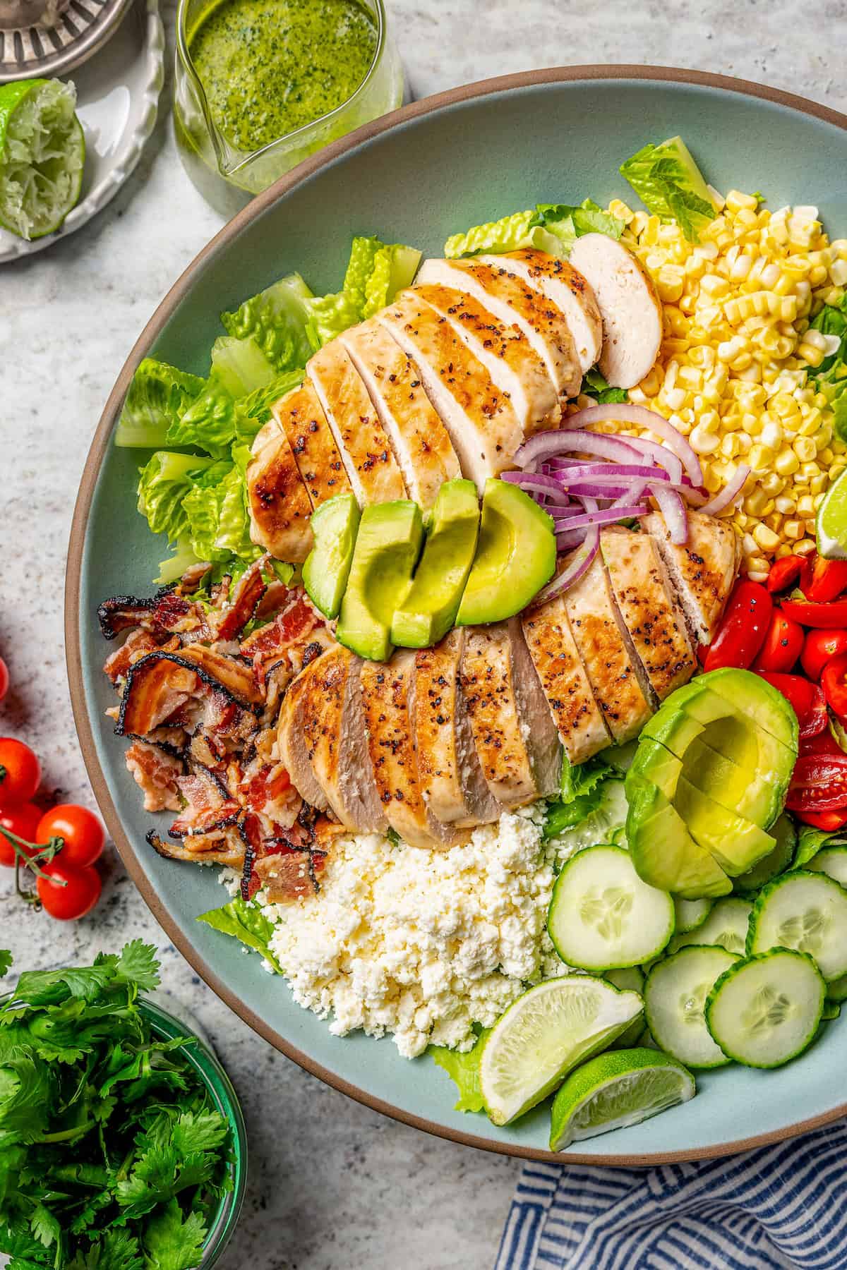 This Grilled Chicken Salad combines fresh corn, creamy avocado and juicy tomatoes with a zippy cilantro-lime vinaigrette for one tasty salad! Overhead view of grilled chicken salad on platter