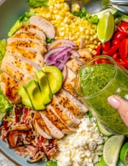 Pouring cilantro lime vinaigrette onto grilled chicken salad
