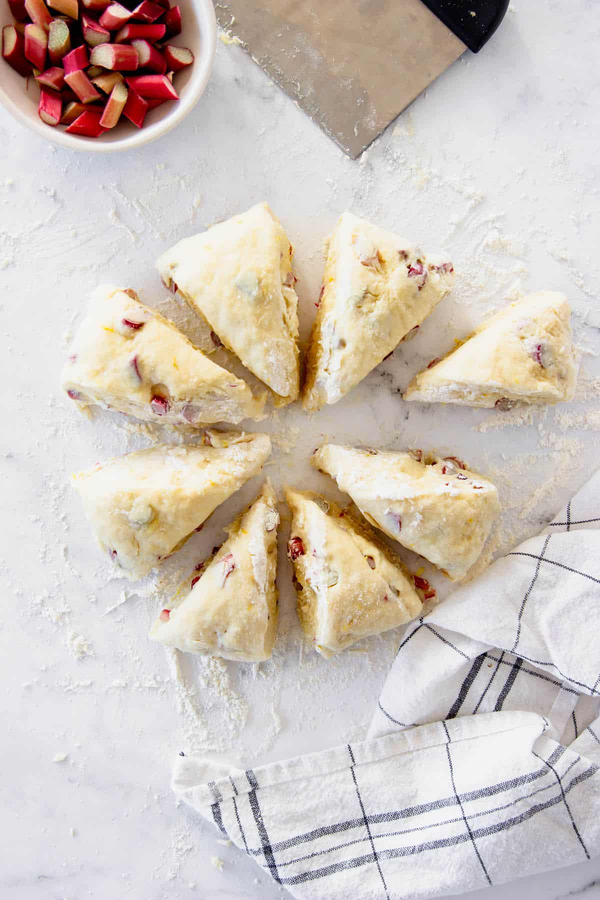 These rhubarb scones are moist inside and flaky outside, filled with juicy tart rhubarb and fresh lemon zest. Perfect with coffee or tea! Lemon rhubarb dough shaped into scones
