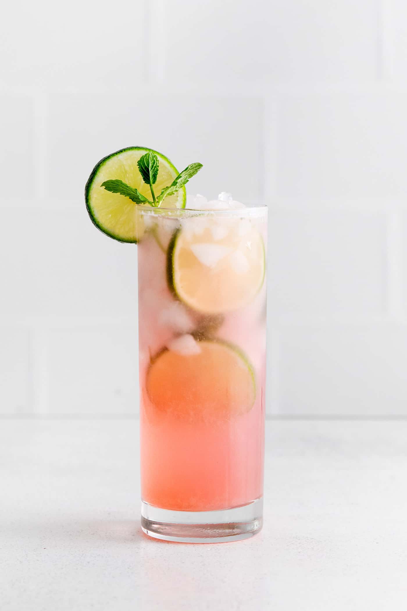 Relax by the pool this summer with a tall, cool Rhubarb Mojito. This twist on the classic cocktail is incredibly refreshing! Rhubarb mojito garnished with lime slice