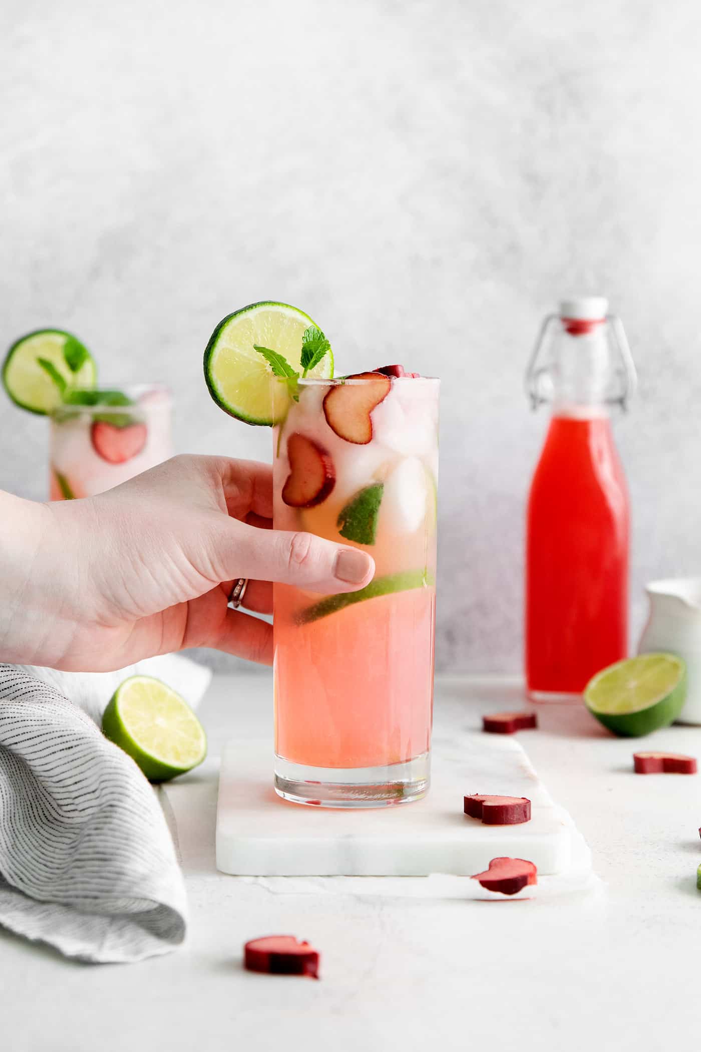 Relax by the pool this summer with a tall, cool Rhubarb Mojito. This twist on the classic cocktail is incredibly refreshing! A hand grabbing a rhubarb mojito