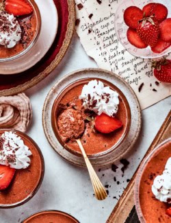Chocolate mousse cups with whipped cream, strawberry, and chocolate shavings.