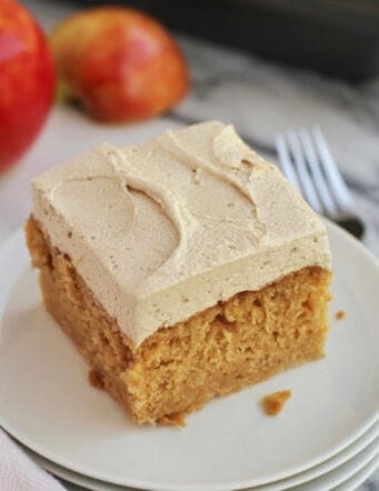 A slice of frosted apple cake on a plate