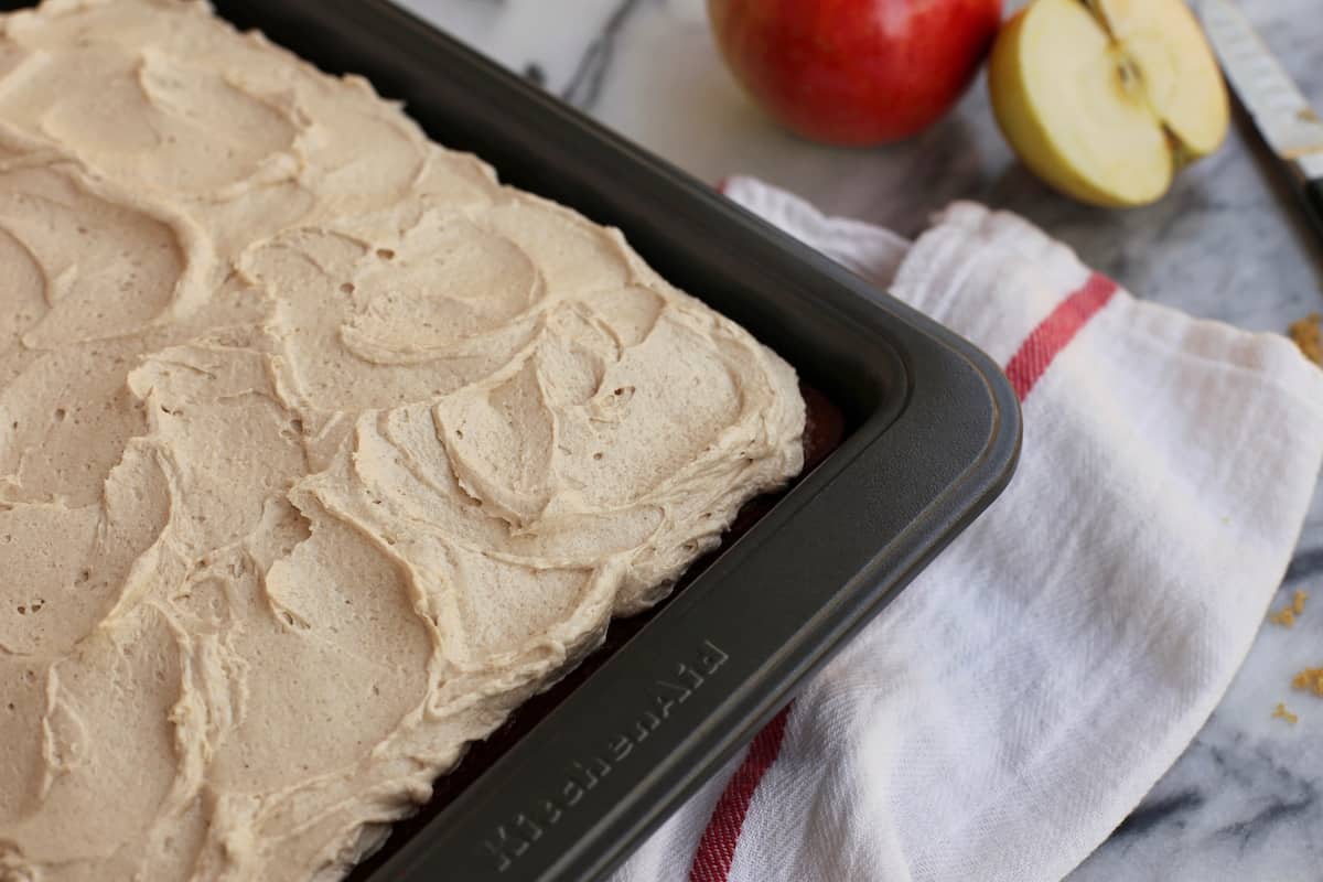 This easy apple cake is a moist, fluffy fall cake recipe filled with warm spice and fresh apples, frosted with brown sugar buttercream! Frosted apple cake in a pan
