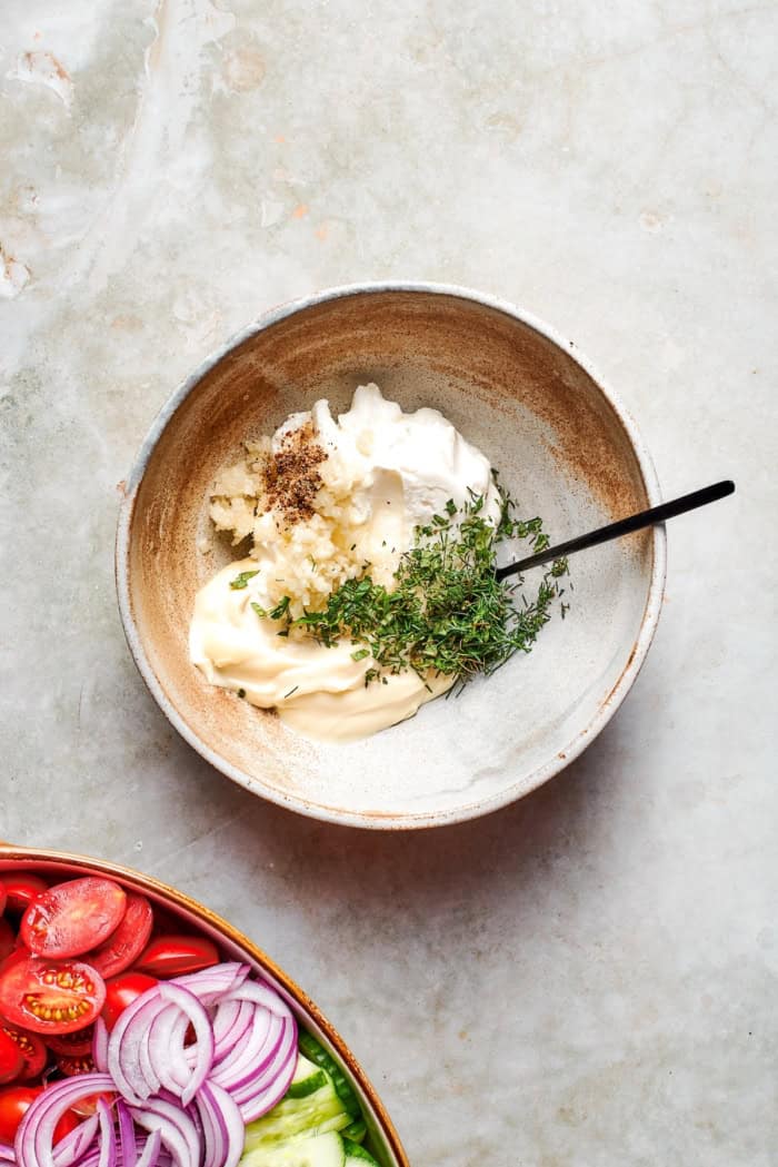 Ingredients for creamy dressing in bowl with spoon.