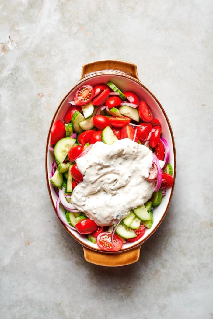 Creamy dressing added to cucumbers, tomatoes, and red onion.