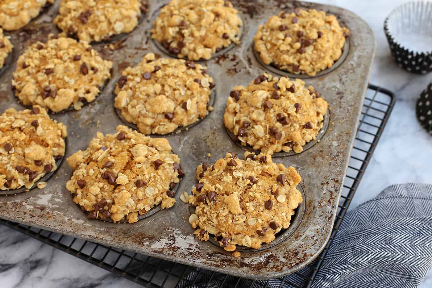 Super moist and perfectly spiced, this pumpkin muffins recipe features a crispy, buttery oat streusel dotted with melty chocolate chips. Pumpkin streusel muffins in a muffin tin.